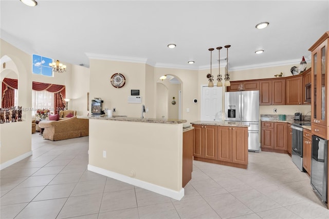 kitchen with a kitchen island with sink, hanging light fixtures, appliances with stainless steel finishes, brown cabinets, and glass insert cabinets