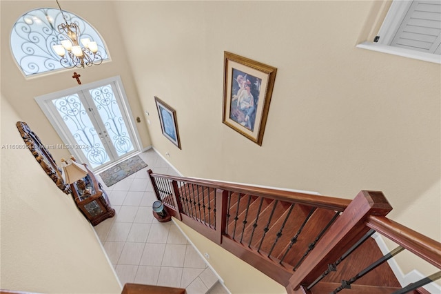 foyer entrance featuring light tile patterned floors, stairway, a chandelier, and french doors