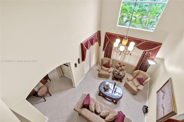 tiled living area featuring a towering ceiling, an inviting chandelier, and baseboards