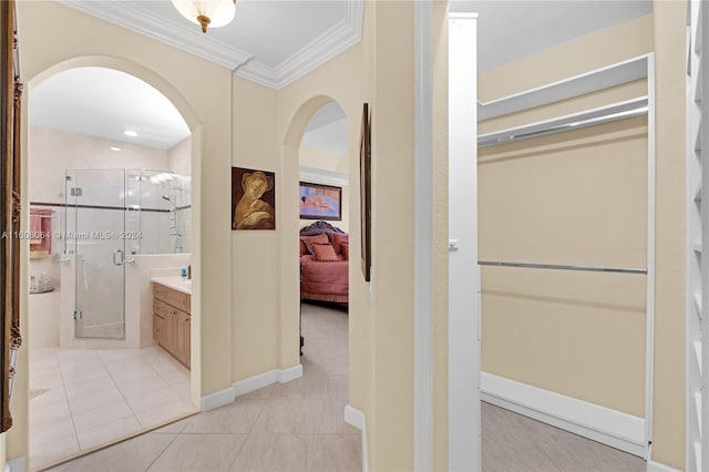 hall featuring arched walkways, crown molding, and baseboards