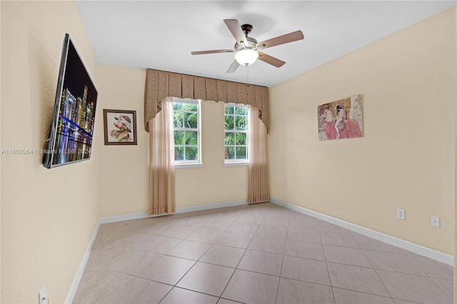 unfurnished room featuring light tile patterned flooring, a ceiling fan, and baseboards