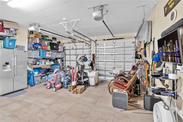 garage with stainless steel fridge and a garage door opener