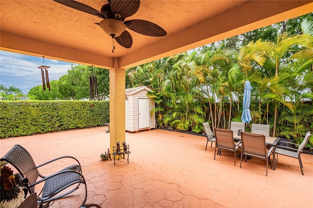 view of patio / terrace featuring a shed, outdoor dining area, a ceiling fan, and an outbuilding