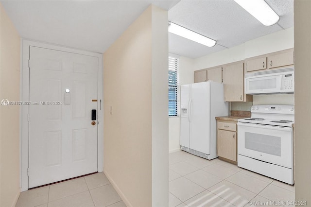 kitchen featuring light tile patterned floors, white appliances, a textured ceiling, and light brown cabinetry