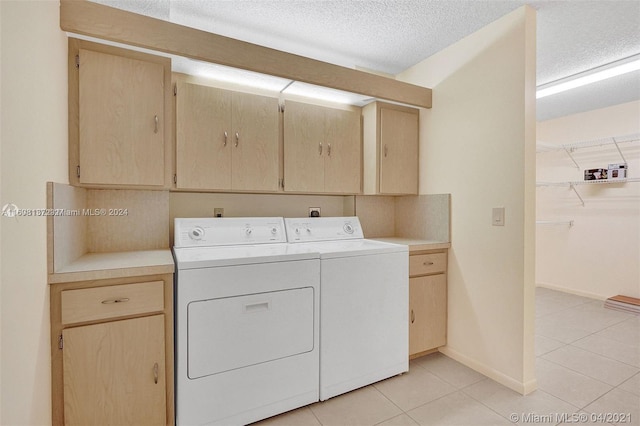 laundry area with separate washer and dryer, light tile patterned floors, cabinets, and a textured ceiling