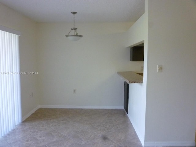 unfurnished dining area featuring plenty of natural light, light tile flooring, and a textured ceiling