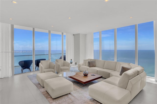 living room with tile flooring, a healthy amount of sunlight, a wall of windows, and a water view