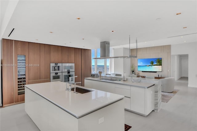 kitchen featuring an island with sink, white cabinetry, sink, and light tile floors