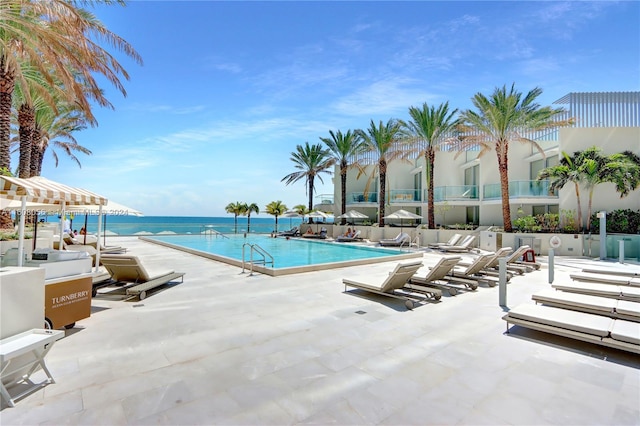 view of swimming pool featuring a water view and a patio