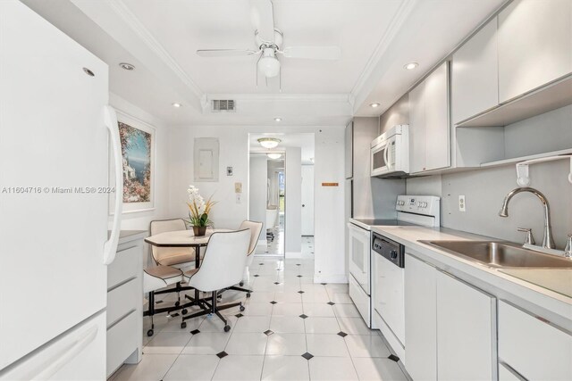 kitchen with a tray ceiling, white appliances, light tile floors, sink, and white cabinets