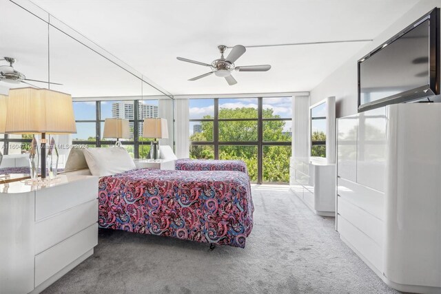 bedroom featuring ceiling fan, a wall of windows, and light colored carpet