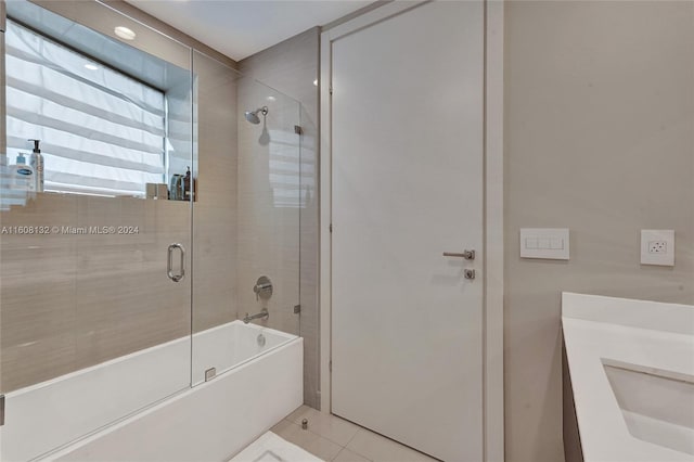 bathroom featuring tile patterned flooring, vanity, and enclosed tub / shower combo