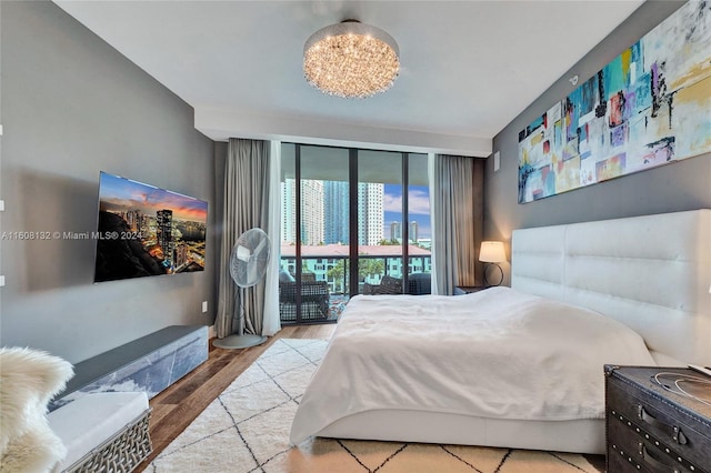 bedroom featuring access to exterior, a chandelier, and light hardwood / wood-style flooring