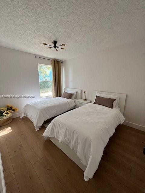 bedroom with a textured ceiling, ceiling fan, and dark wood-type flooring