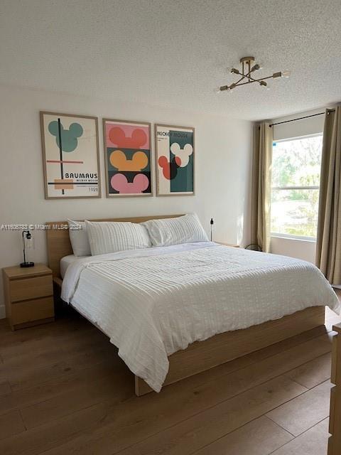 bedroom featuring hardwood / wood-style flooring, a textured ceiling, and a chandelier