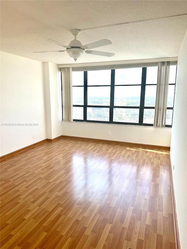 unfurnished room with ceiling fan, a textured ceiling, and hardwood / wood-style flooring