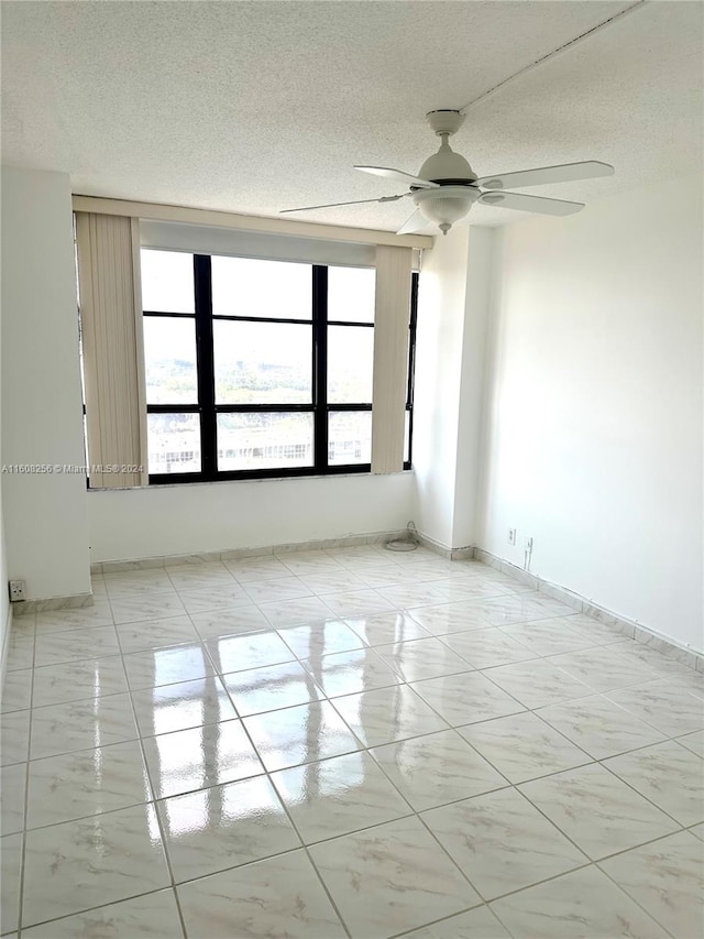 tiled empty room featuring ceiling fan and a textured ceiling