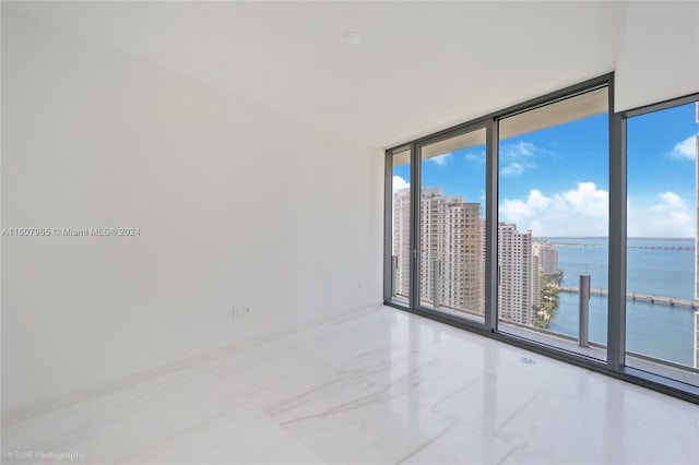 empty room featuring tile flooring, expansive windows, and a water view