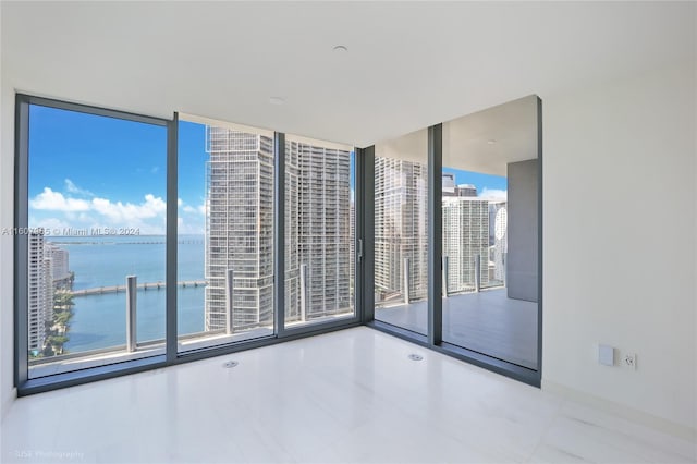 unfurnished room featuring a water view, expansive windows, and tile flooring