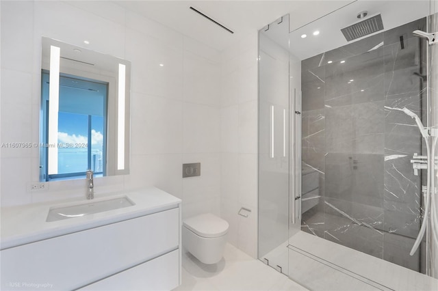 bathroom with a tile shower, vanity with extensive cabinet space, tile walls, and toilet