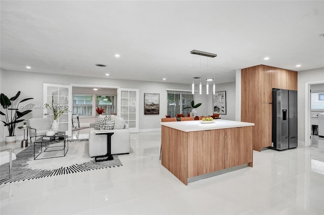 kitchen featuring stainless steel fridge, a kitchen island, pendant lighting, and light tile patterned flooring