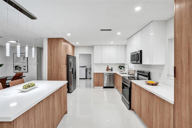 kitchen featuring stainless steel appliances, sink, light tile patterned floors, white cabinets, and hanging light fixtures