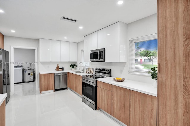 kitchen with white cabinetry, sink, washer / clothes dryer, light tile patterned floors, and appliances with stainless steel finishes