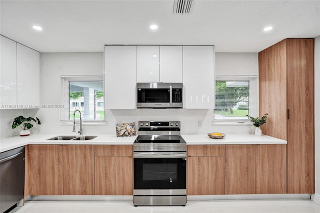 kitchen with white cabinets, plenty of natural light, sink, and appliances with stainless steel finishes