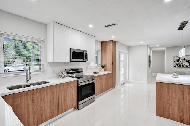 kitchen with white cabinets, sink, light tile patterned floors, appliances with stainless steel finishes, and decorative light fixtures