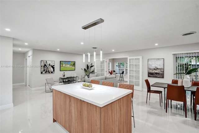 kitchen featuring decorative light fixtures, a kitchen island, light tile patterned flooring, and a wealth of natural light