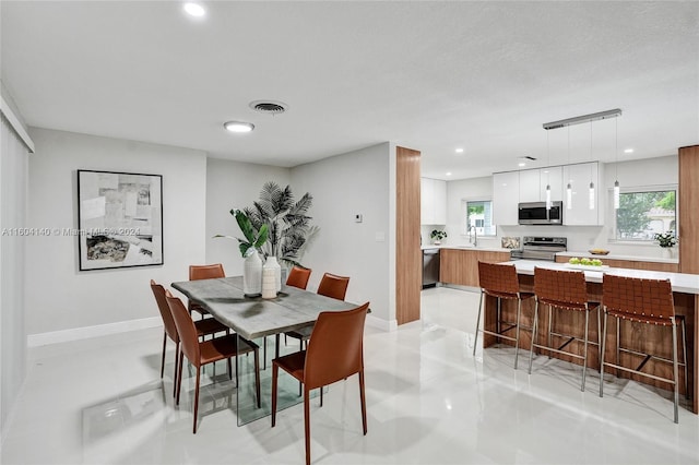 dining space featuring sink, light tile patterned flooring, and a textured ceiling