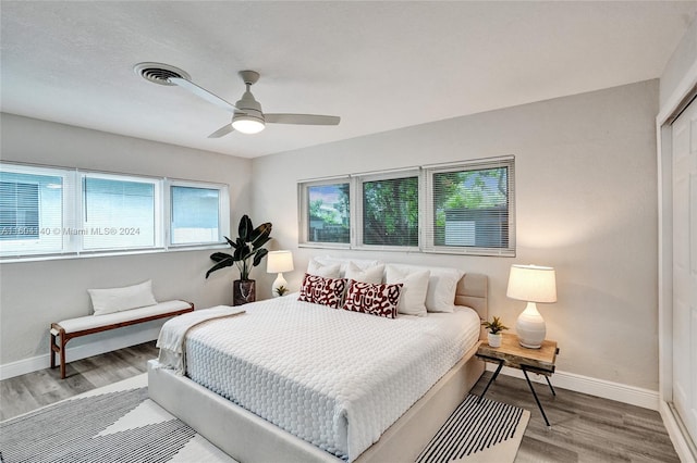 bedroom with multiple windows, ceiling fan, a closet, and hardwood / wood-style flooring