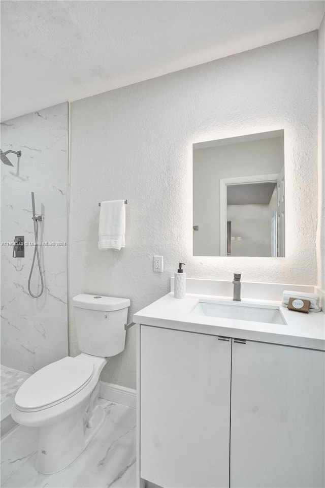 bathroom with tiled shower, vanity, a textured ceiling, and toilet