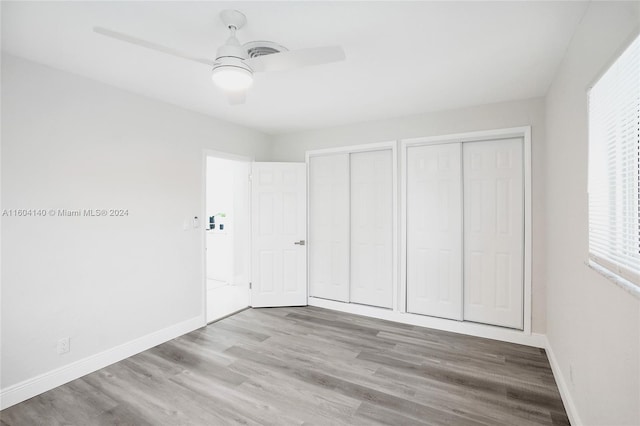 unfurnished bedroom with ceiling fan, light hardwood / wood-style flooring, and two closets