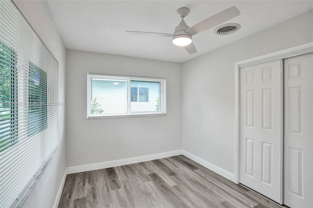 unfurnished bedroom with ceiling fan, a closet, and light wood-type flooring