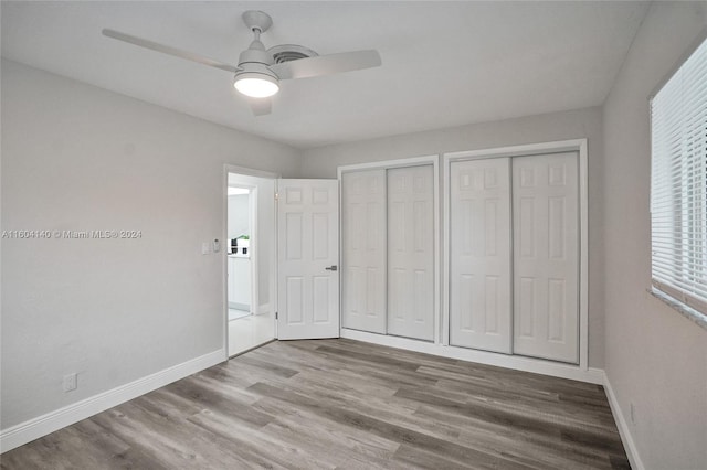 unfurnished bedroom featuring two closets, light hardwood / wood-style flooring, and ceiling fan