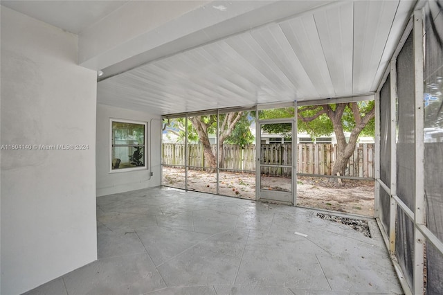 unfurnished sunroom with beam ceiling