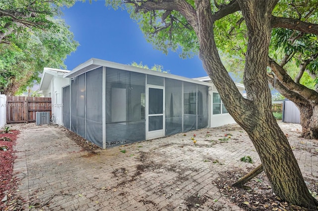 rear view of property featuring a sunroom and cooling unit