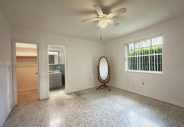 unfurnished bedroom featuring ceiling fan, a spacious closet, connected bathroom, and a closet