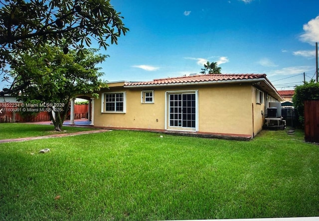 rear view of property featuring a yard and cooling unit