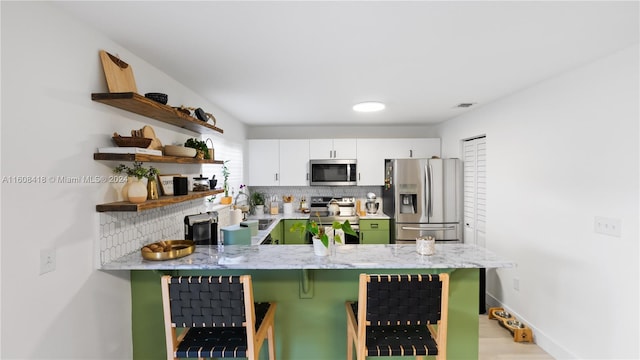 kitchen with white cabinetry, stainless steel appliances, tasteful backsplash, and kitchen peninsula