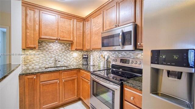 kitchen featuring dark stone counters, stainless steel appliances, tasteful backsplash, sink, and light tile floors