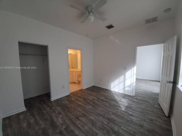 unfurnished bedroom with ceiling fan, ensuite bath, dark wood-type flooring, and a closet