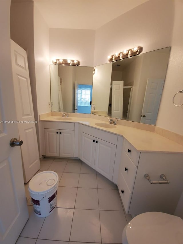 bathroom featuring double vanity, a sink, tile patterned floors, and toilet