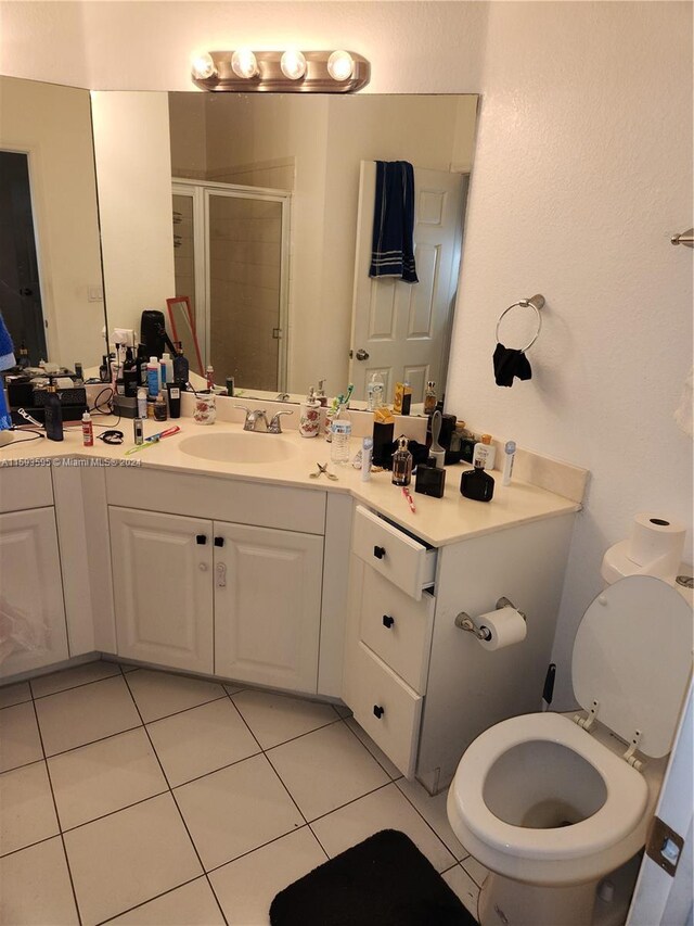 bathroom with tile patterned flooring, vanity, toilet, and a shower with door