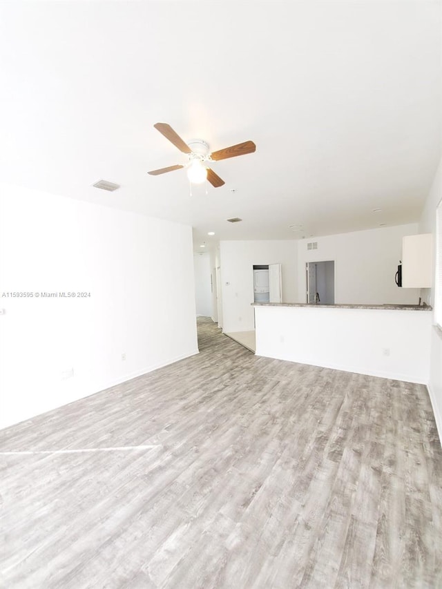 unfurnished living room with ceiling fan and light wood-type flooring