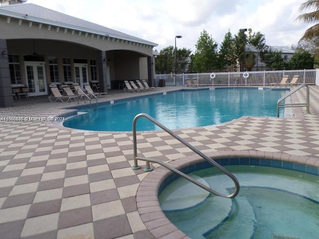 view of swimming pool featuring a community hot tub, a patio, and french doors