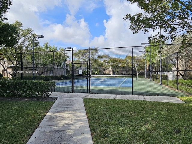 view of tennis court featuring a yard