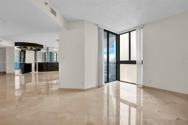 spare room featuring a textured ceiling and a wall of windows