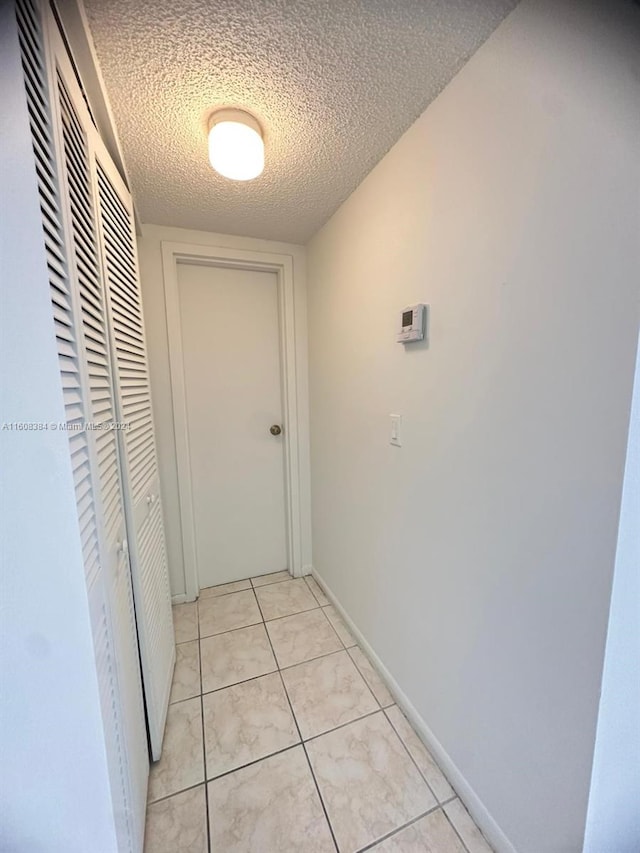 hall with light tile patterned floors and a textured ceiling